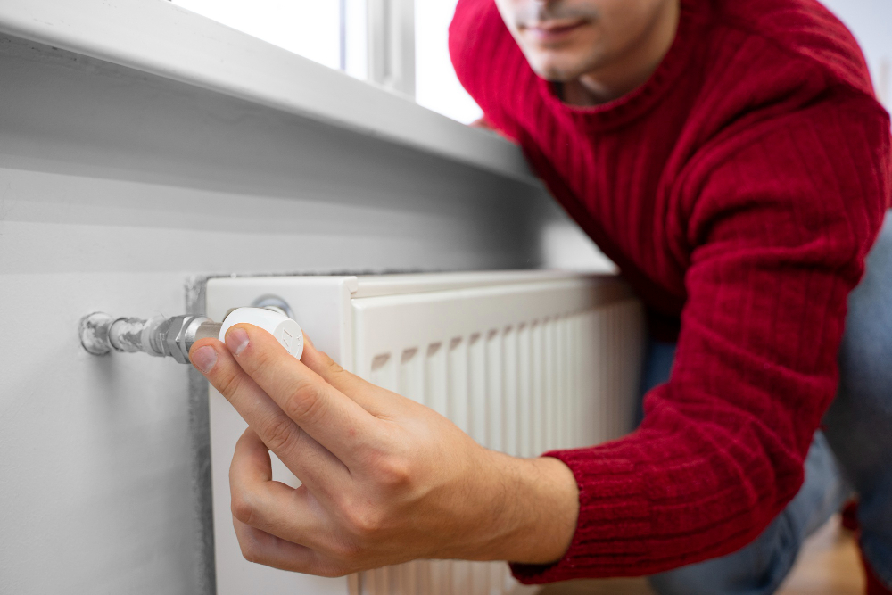 Chauffagiste règle un thermostat de radiateur